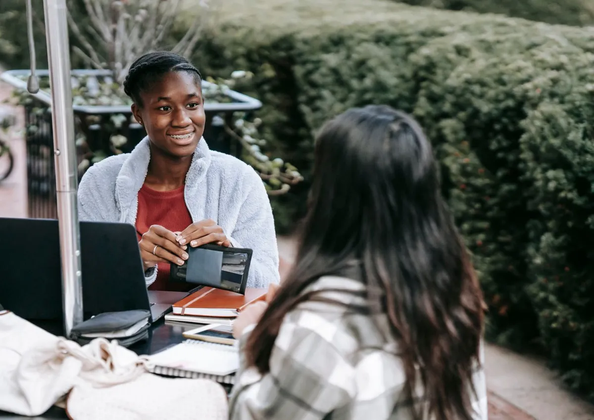 Young adults sharing ideas while working with a laptop and notebook