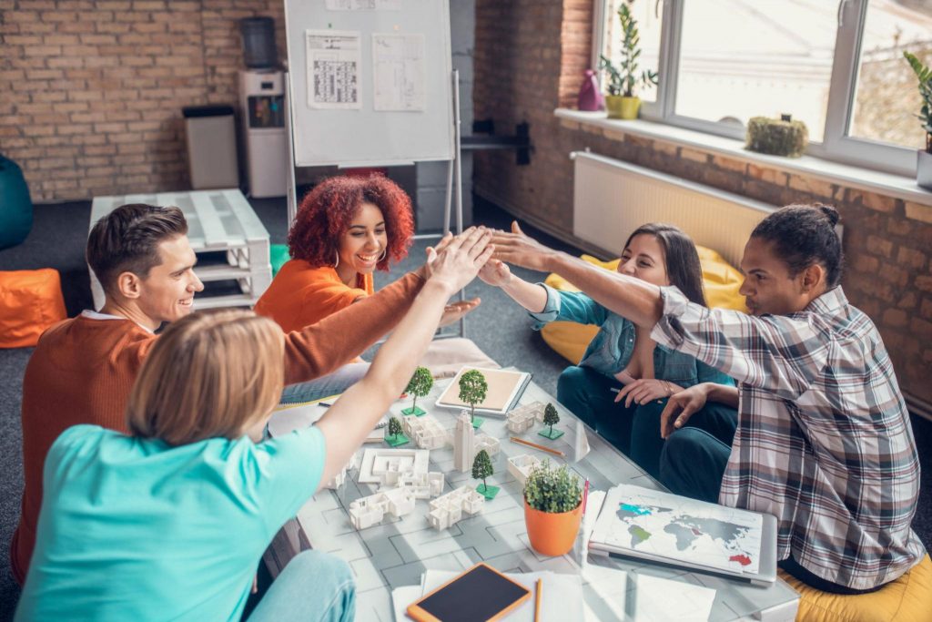 Group of young people collaborating on a project and celebrating success together, representing teamwork, confidence, and shared achievement.