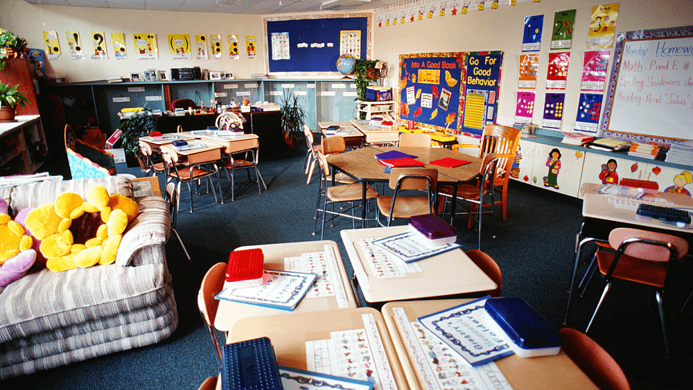 Traditional classroom with desks, educational posters, and teaching materials arranged for structured learning.