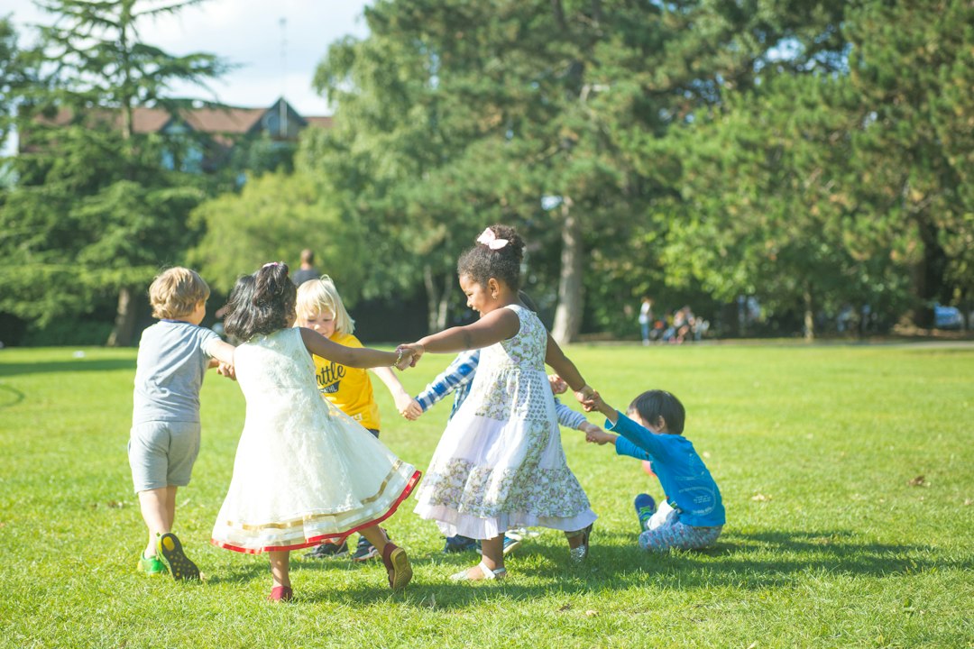 Children holding hands in a circle on a sunny park lawn