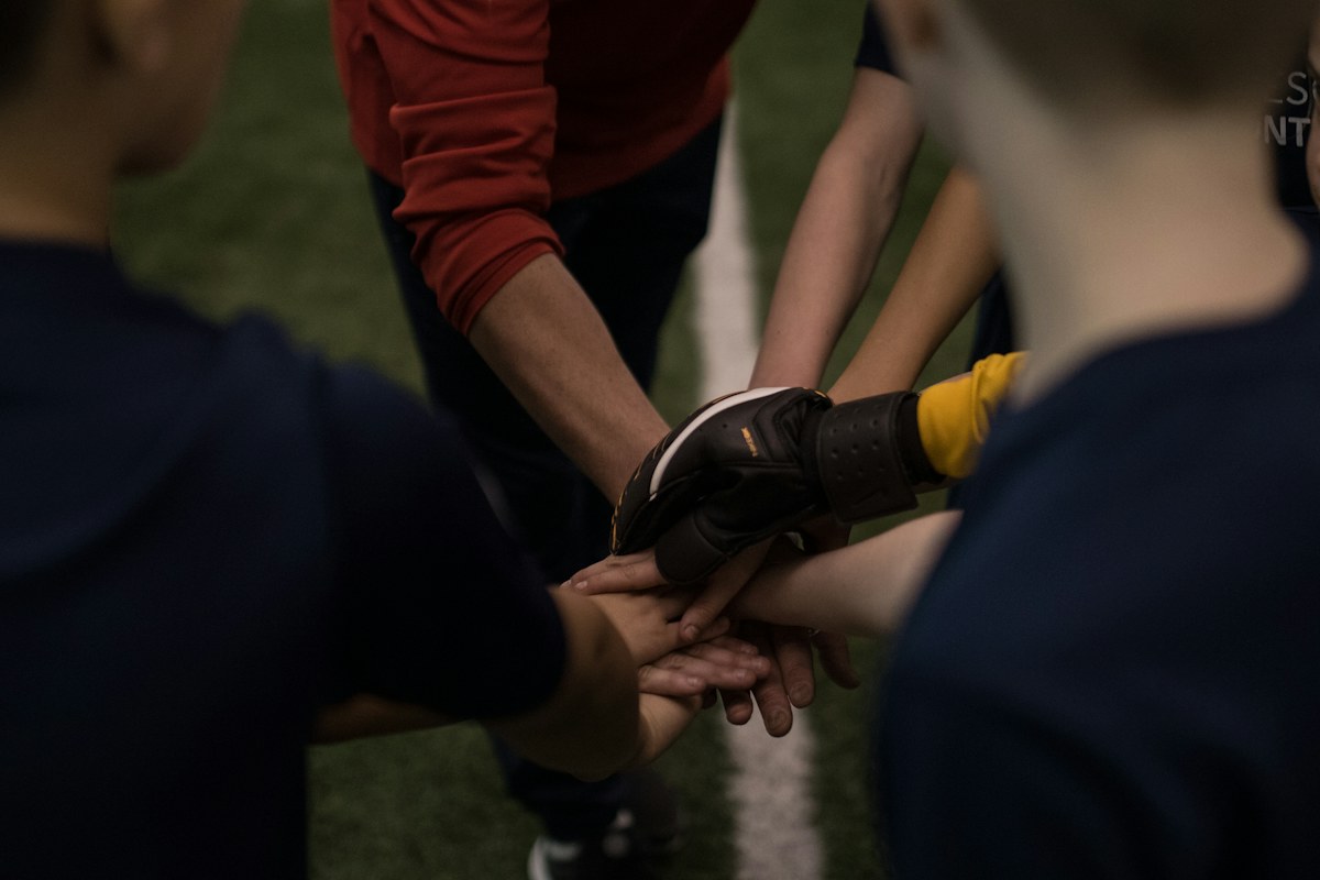 Sports team members placing their hands together before an activity